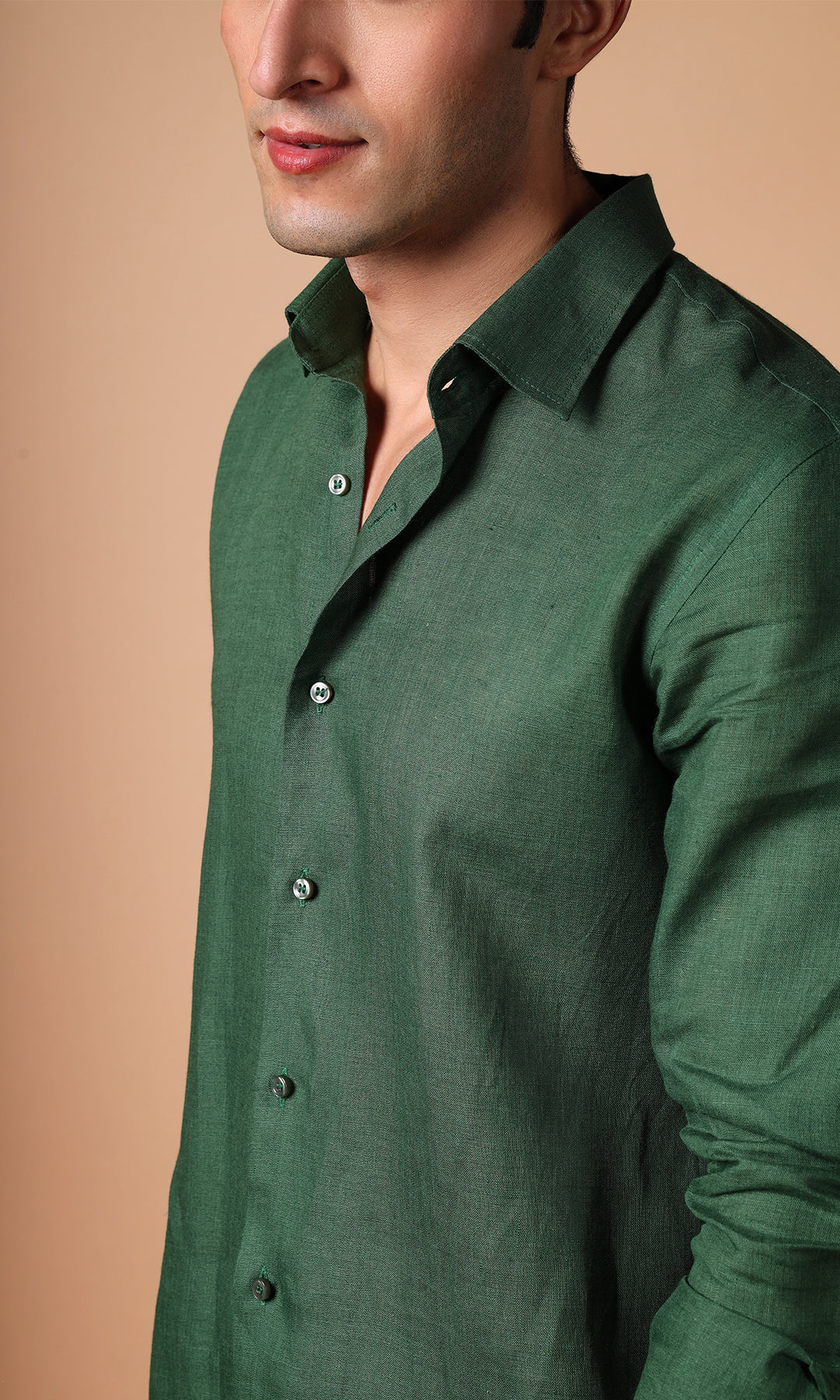 Close-up of an olive green linen shirt on a model, showcasing the subtle green hue and fine weave