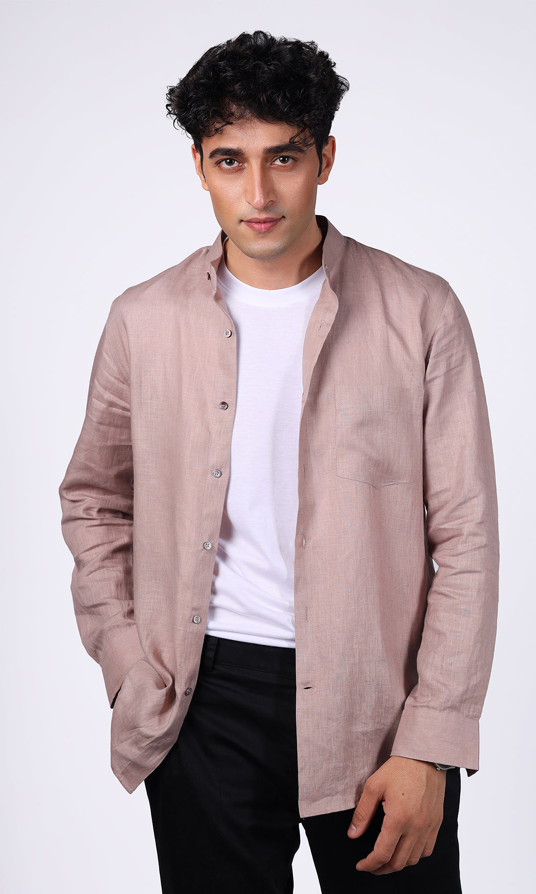 Half length view of a model wearing a pink linen overshirt, styled unbuttoned for a relaxed and fashionable appearance, great for summer wear.
