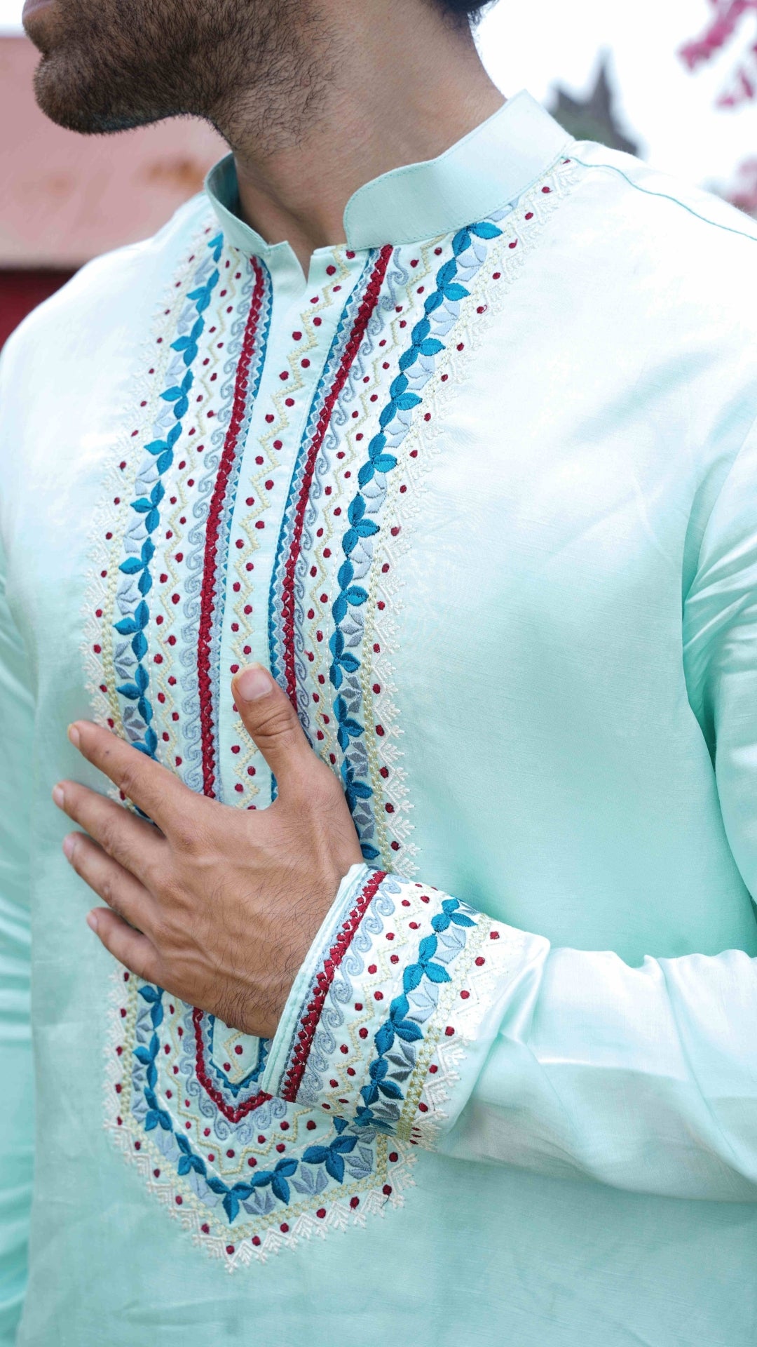 Light blue embroidered shirt with red and white patterns on a blurred background