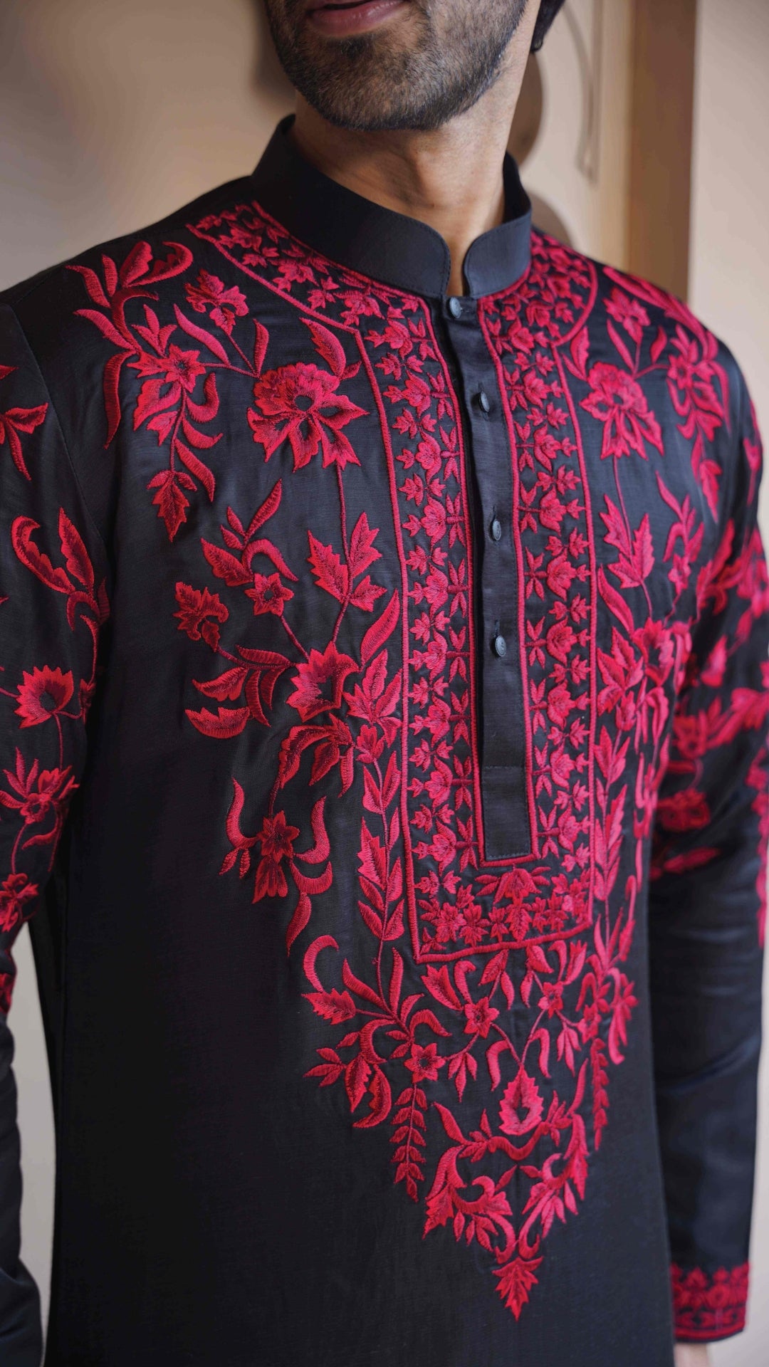 Black shirt with red floral embroidery worn by a person