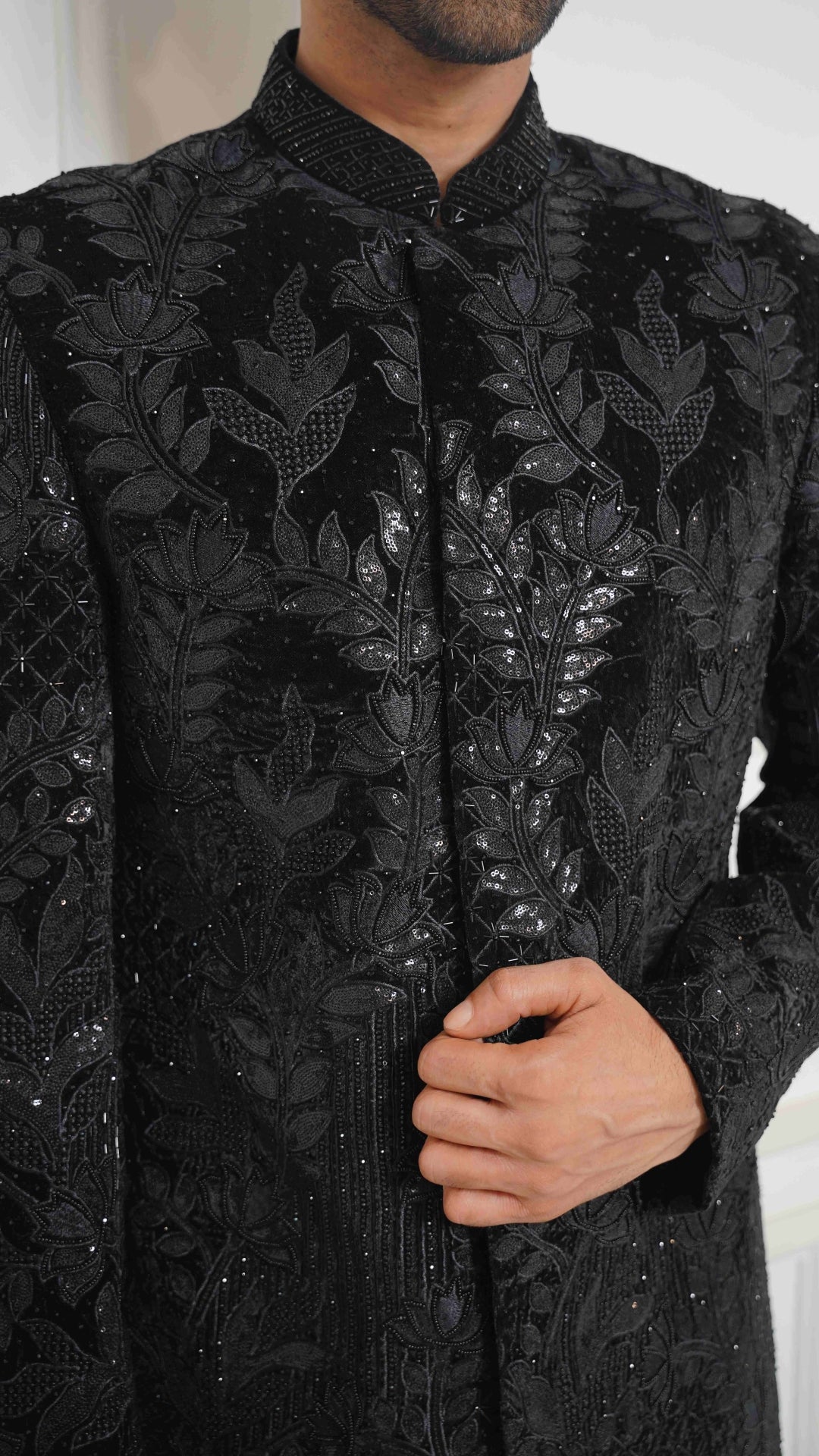 Black embroidered sherwani worn by a person with a blurred background
