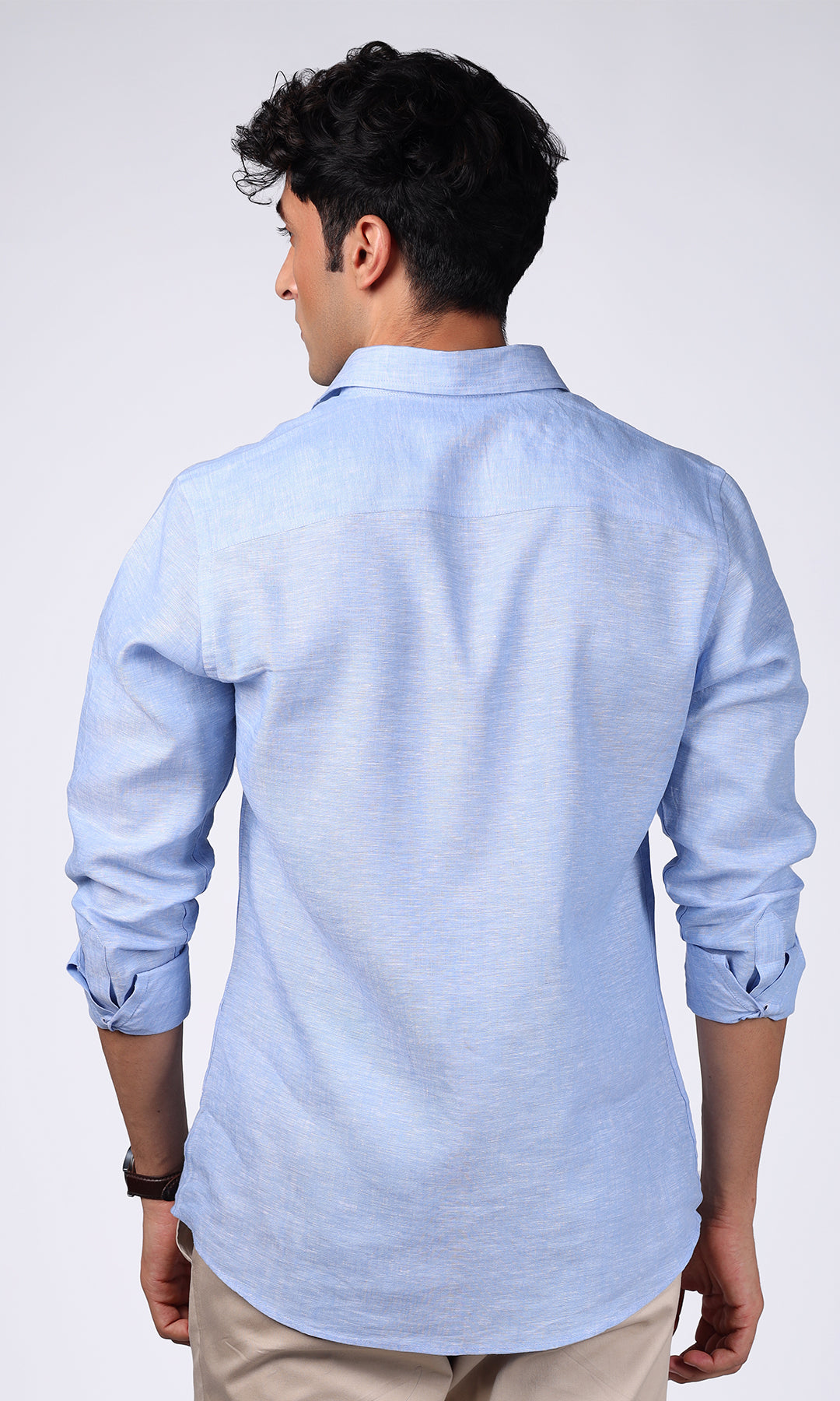 Close-up on a sky blue linen shirt worn by a model, featuring the fabric's fine weave.