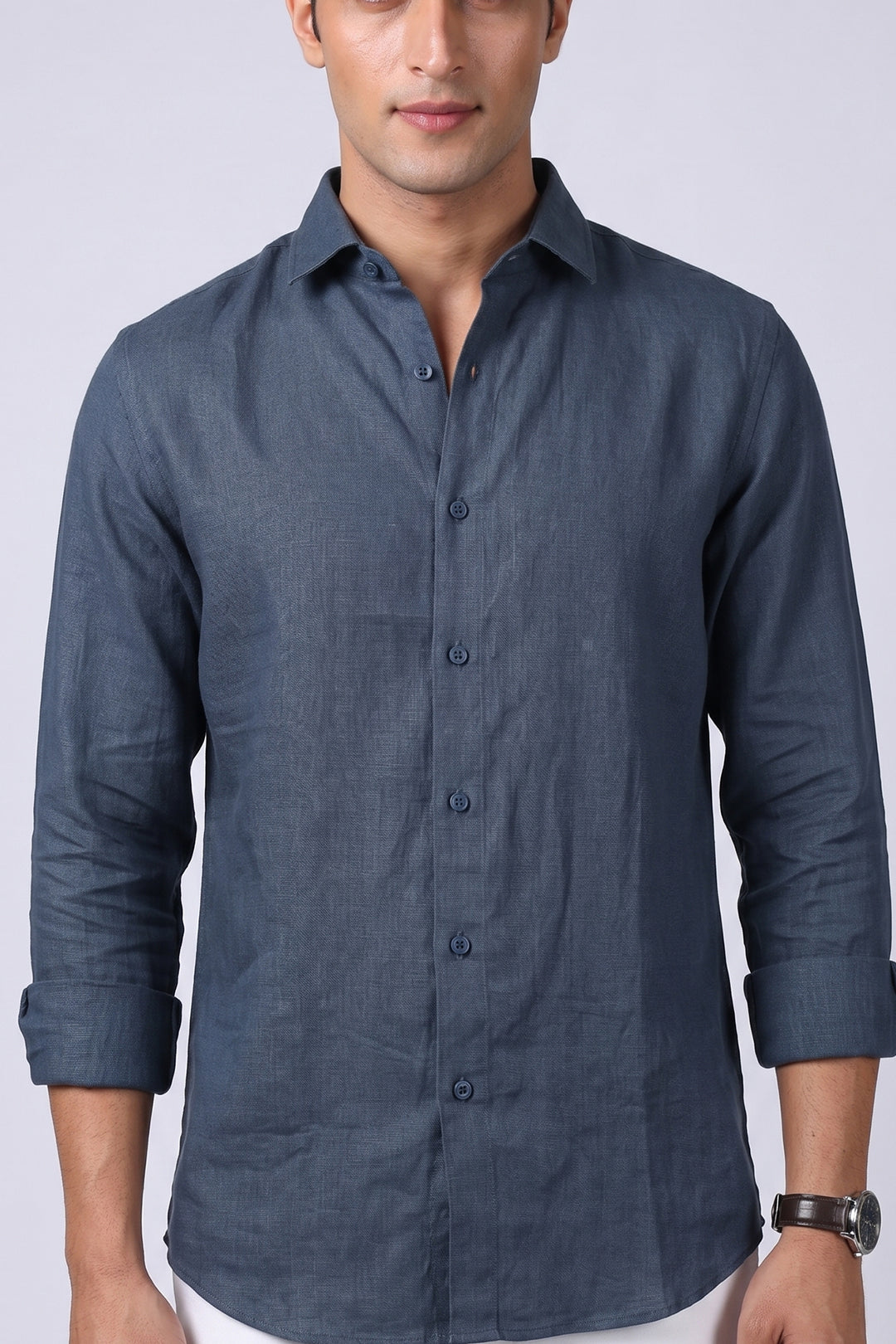 Steel blue pure linen shirt for men, close-up of spread collar, full button placket and end-on-end linen texture, sleeves rolled, styled with white trousers, by BWO