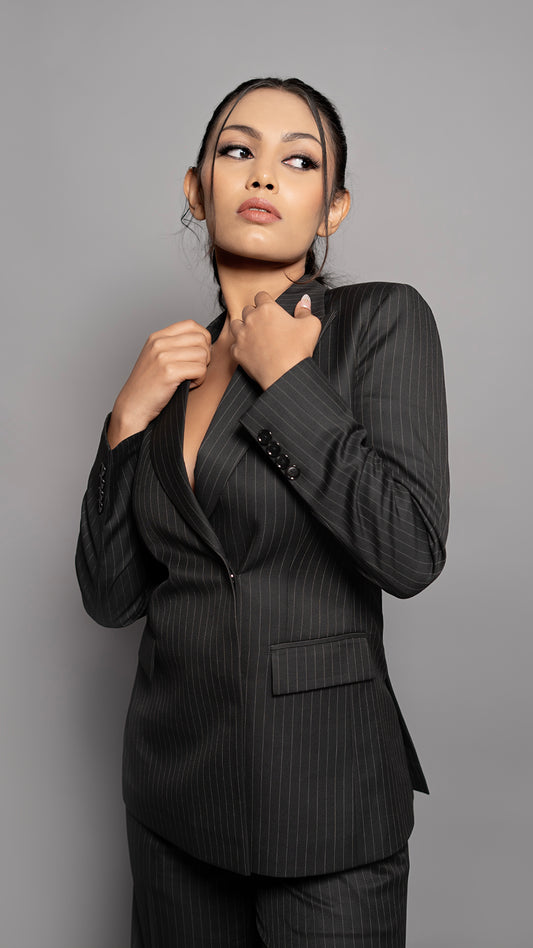 A sharp black pinstriped blazer featuring a refined peak lapel and a sleek concealed button closure for a modern, sophisticated look.