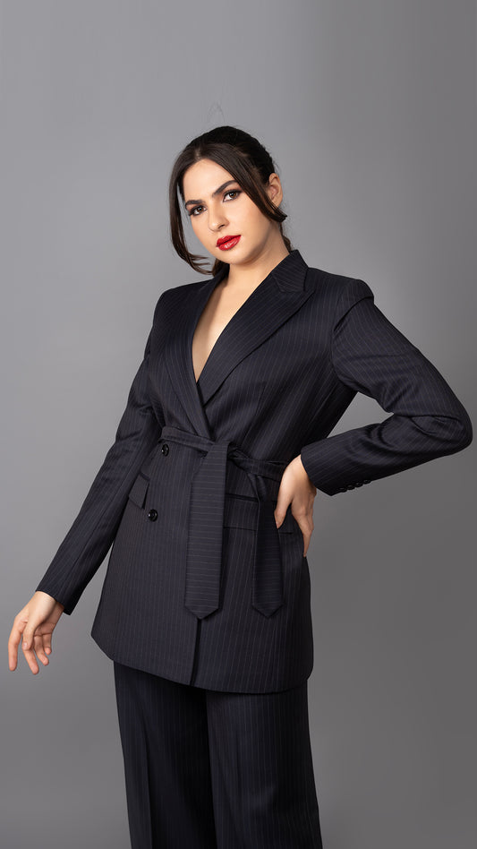 A structured blue pinstriped blazer featuring a sharp peak lapel and a cinched belted waist, blending power dressing with feminine elegance.