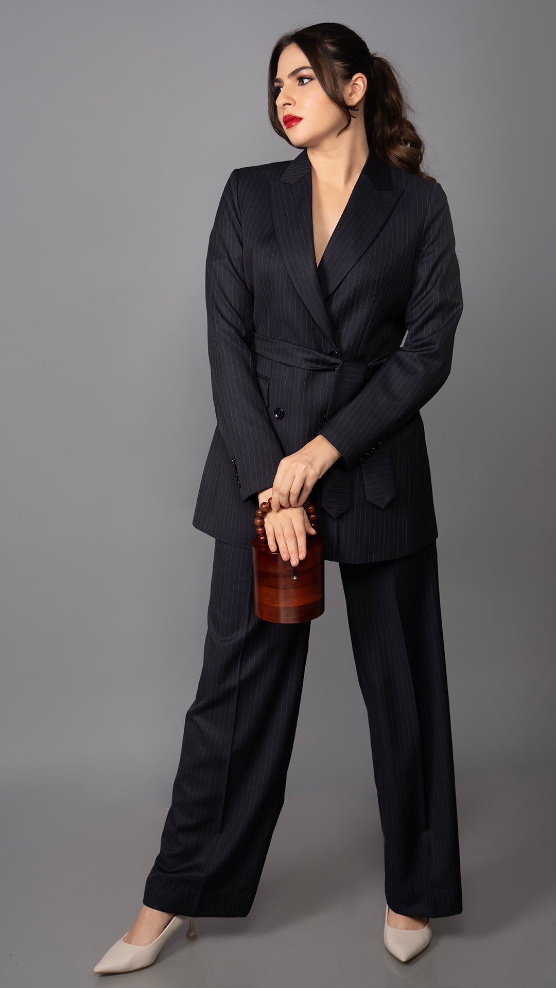 A sophisticated blue pinstriped suit with a structured blazer, peak lapel, and waist belt, paired with sleek tailored trousers.