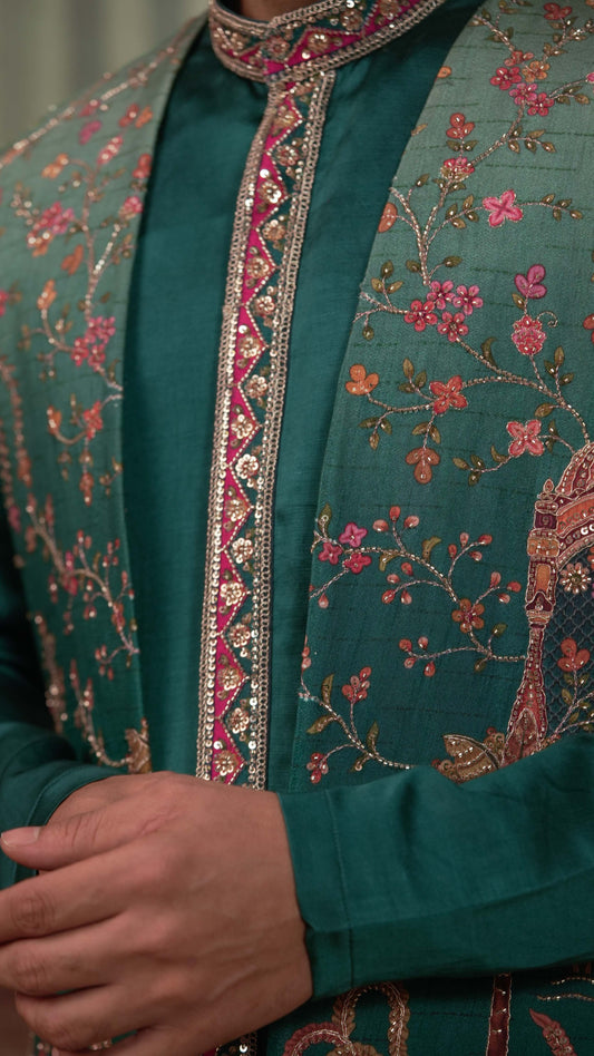 Close-up of a traditional embroidered green kurta with a matching inner shirt, featuring intricate floral embroidery and a decorative pink and gold border.
