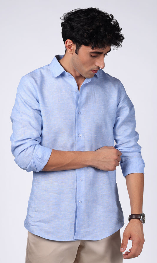 Model in a sky blue linen shirt posing with a relaxed posture, reflecting a calm and collected style.