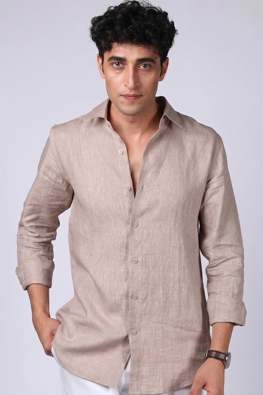 
Greige pure linen shirt for men, front view with collar worn open and hand in pocket, spread collar and long sleeves rolled, styled with white trousers, by BWO