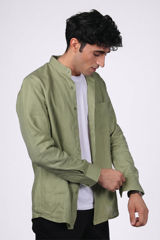 Sage green pure linen shirt for men, side view worn open over white tee, band collar and chest pocket detail, long sleeves with buttoned cuffs, styled with black trousers, by BWO