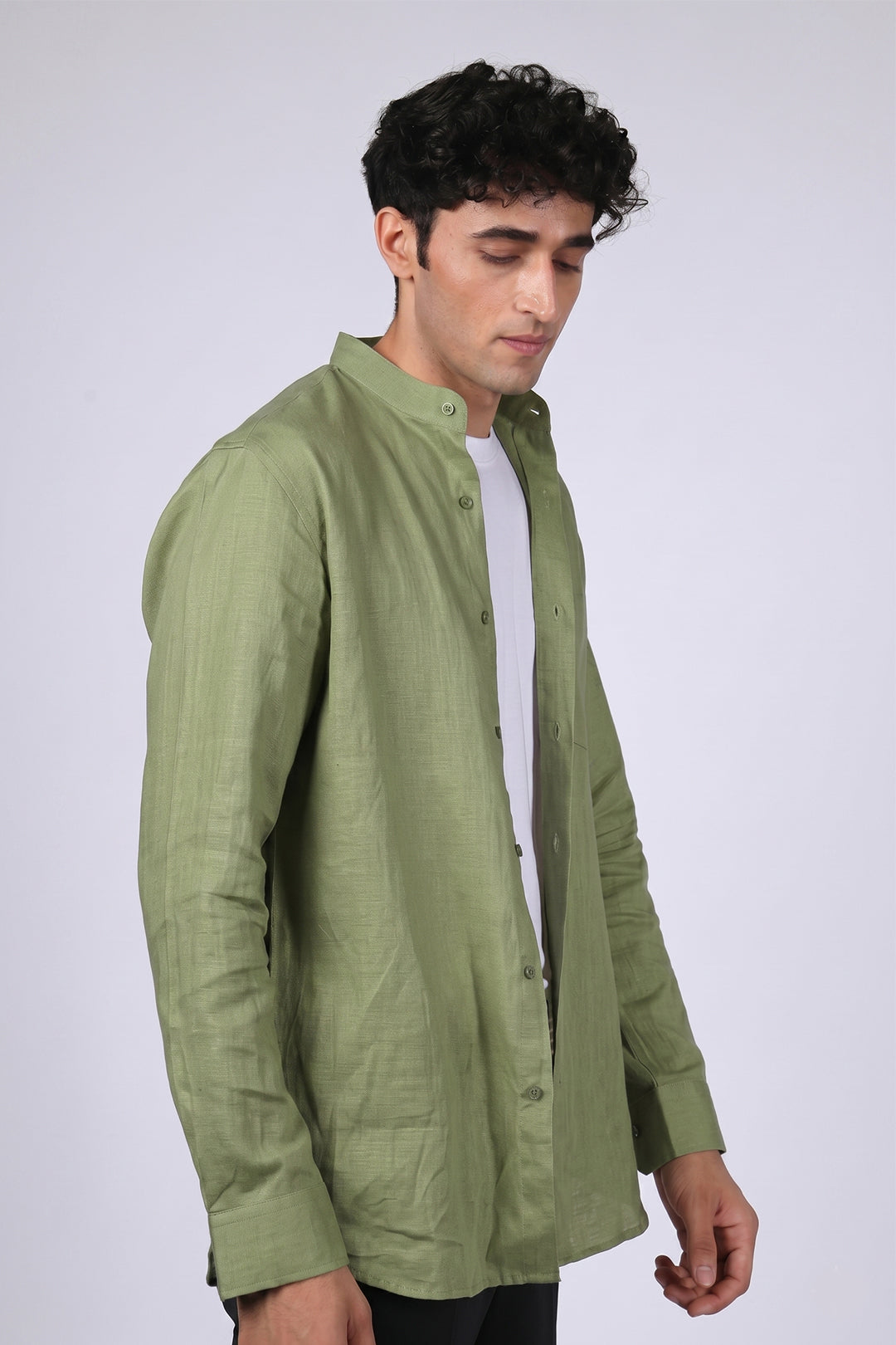 Sage green pure linen shirt for men, side view worn open over white tee, band collar and full button placket visible, long sleeves with buttoned cuffs, styled with black trousers, by BWO