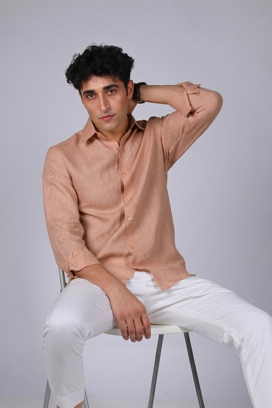 Peach Sandstone pure linen shirt for men, seated pose with hand behind neck, classic spread collar and button placket, styled with white trousers, by BWO
