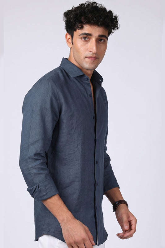 Steel blue pure linen shirt for men, side angle view with collar worn open and sleeves rolled, full button placket visible, styled with white trousers, by BWO