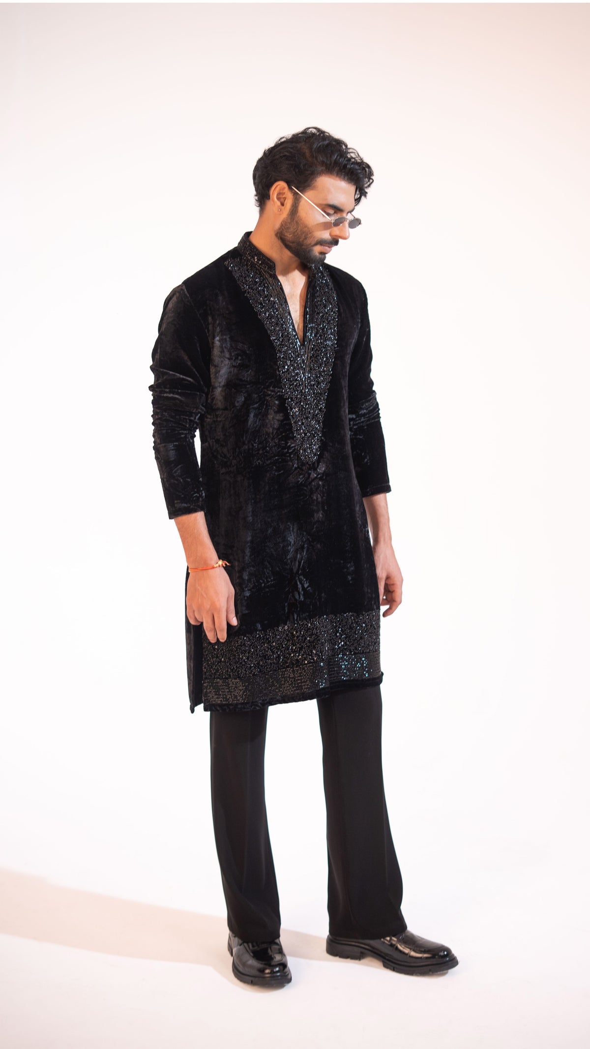 A man modeling a black velvet and cut-dana kurta with black trousers, standing against a plain white studio background.